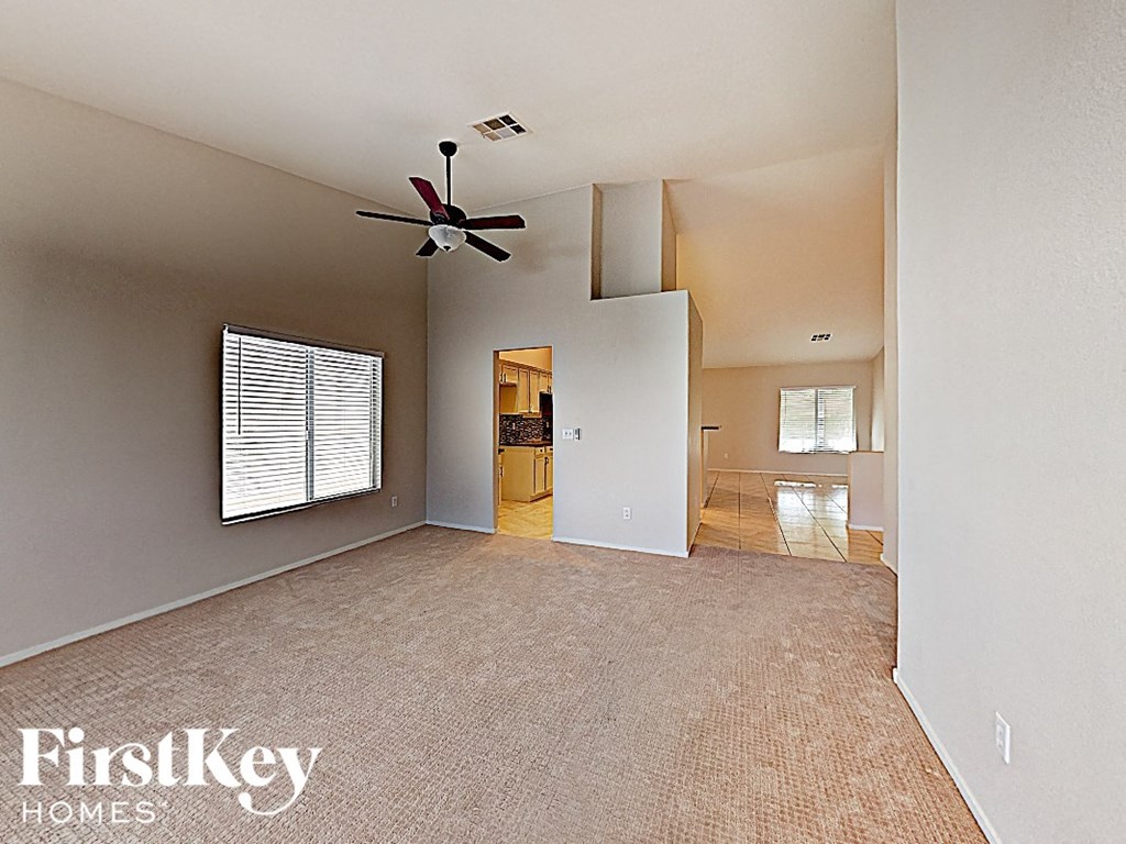 A spacious room with a carpeted floor and a ceiling fan.