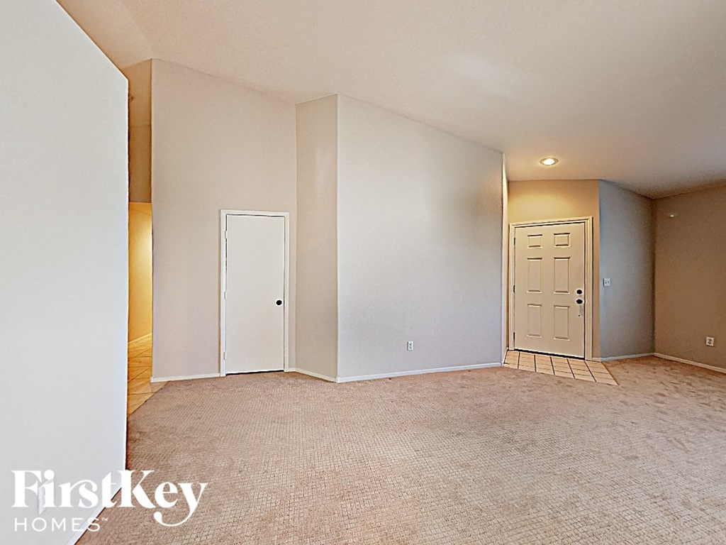 A room with a carpeted floor and two doors.