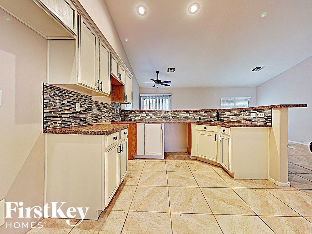 A kitchen with a stone counter top and beige cabinets.