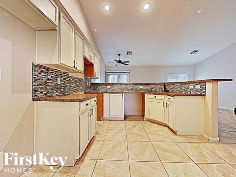 A kitchen with a stone counter top and beige cabinets.