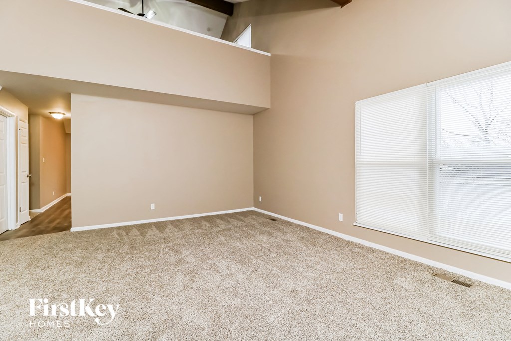 a spacious living room with carpeted flooring and a large window
