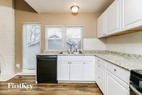 a kitchen with white cabinets and a sink and a window