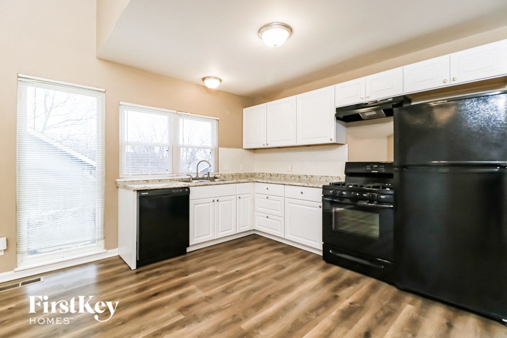 an empty kitchen with black appliances and white cabinets