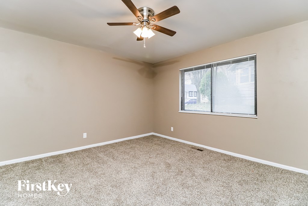 an empty bedroom with a ceiling fan and a window
