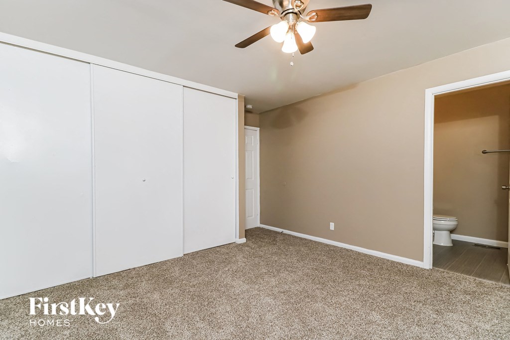 a bedroom with white closets and a ceiling fan