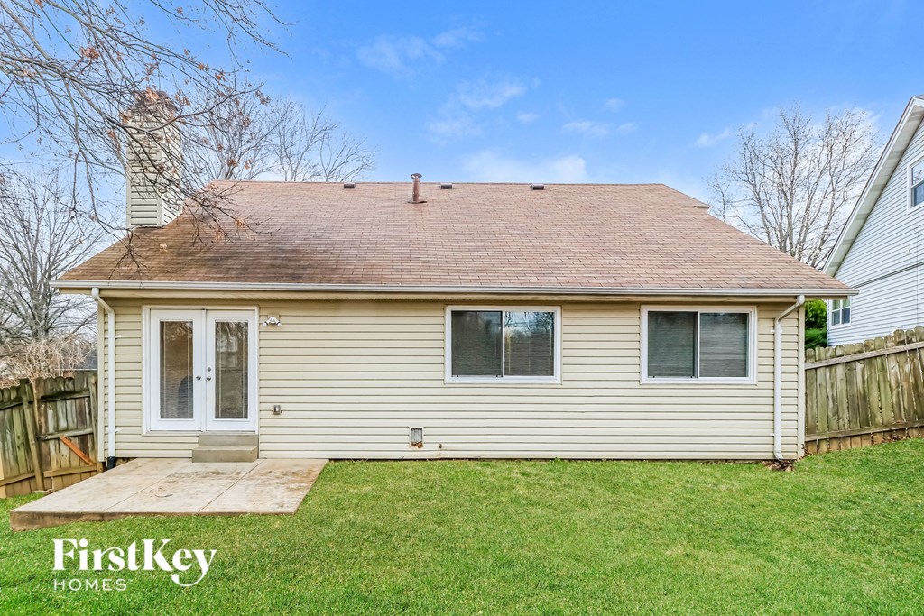 the back of a white house with a yard and a backdoor