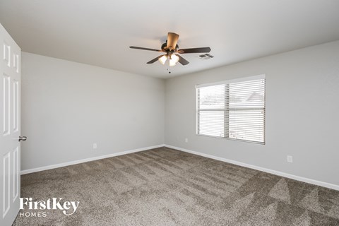 the spacious living room with ceiling fan and carpet