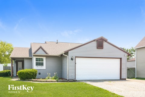 a gray house with a white garage door and a lawn