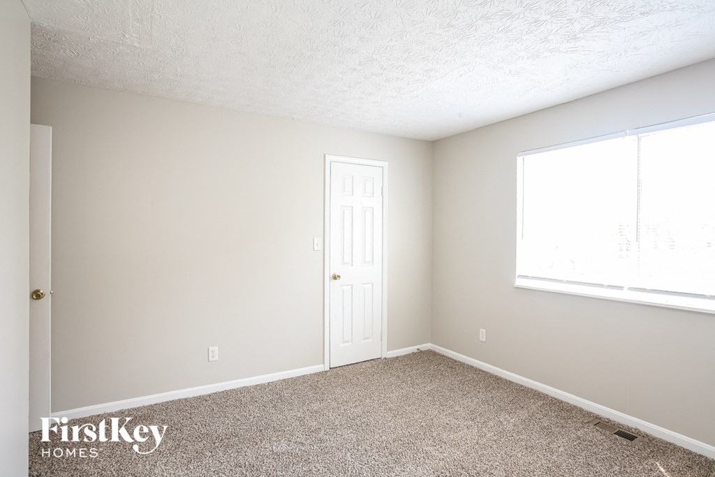 a bedroom with carpet and a door and a window