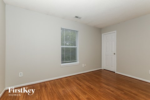 a bedroom with wood flooring and a window and a white door