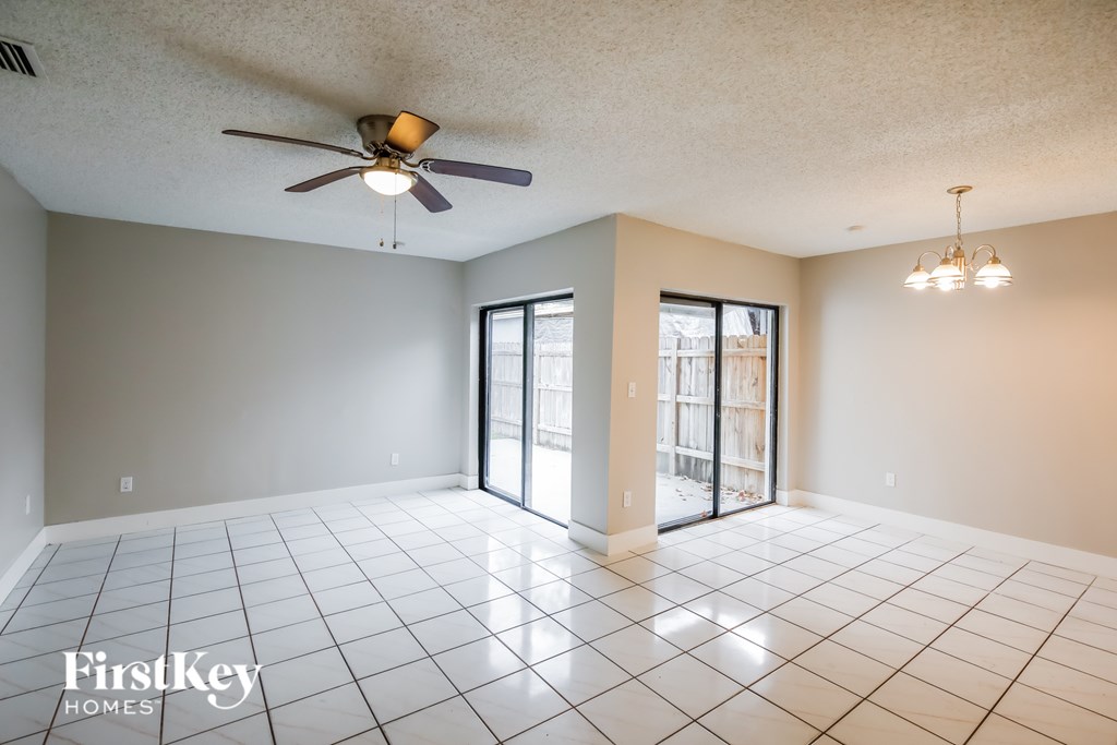 A spacious room with a ceiling fan and sliding glass doors.