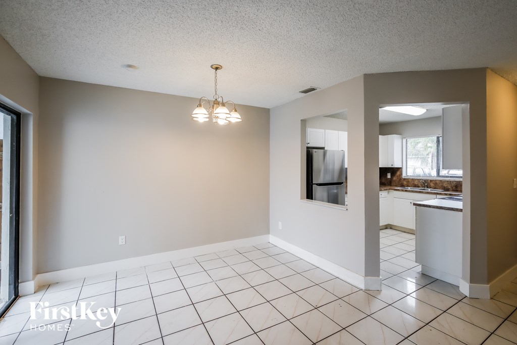 A spacious room with a tiled floor and a chandelier hanging from the ceiling.