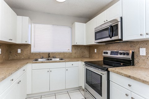 A kitchen with white cabinets and a black microwave.