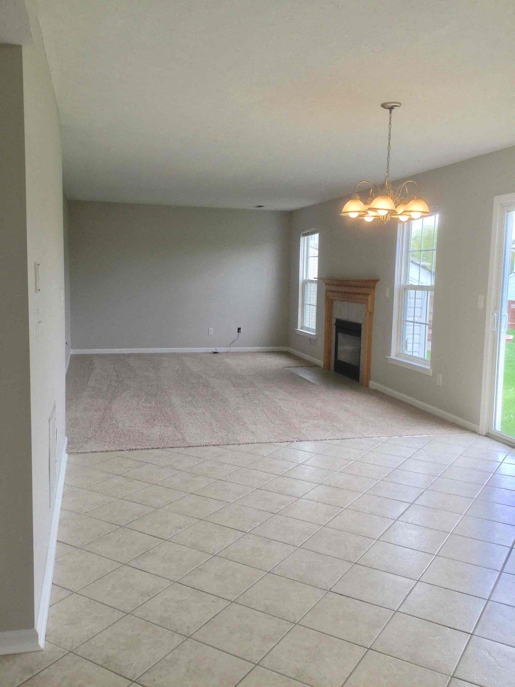 an empty living room with a tile floor and a fireplace