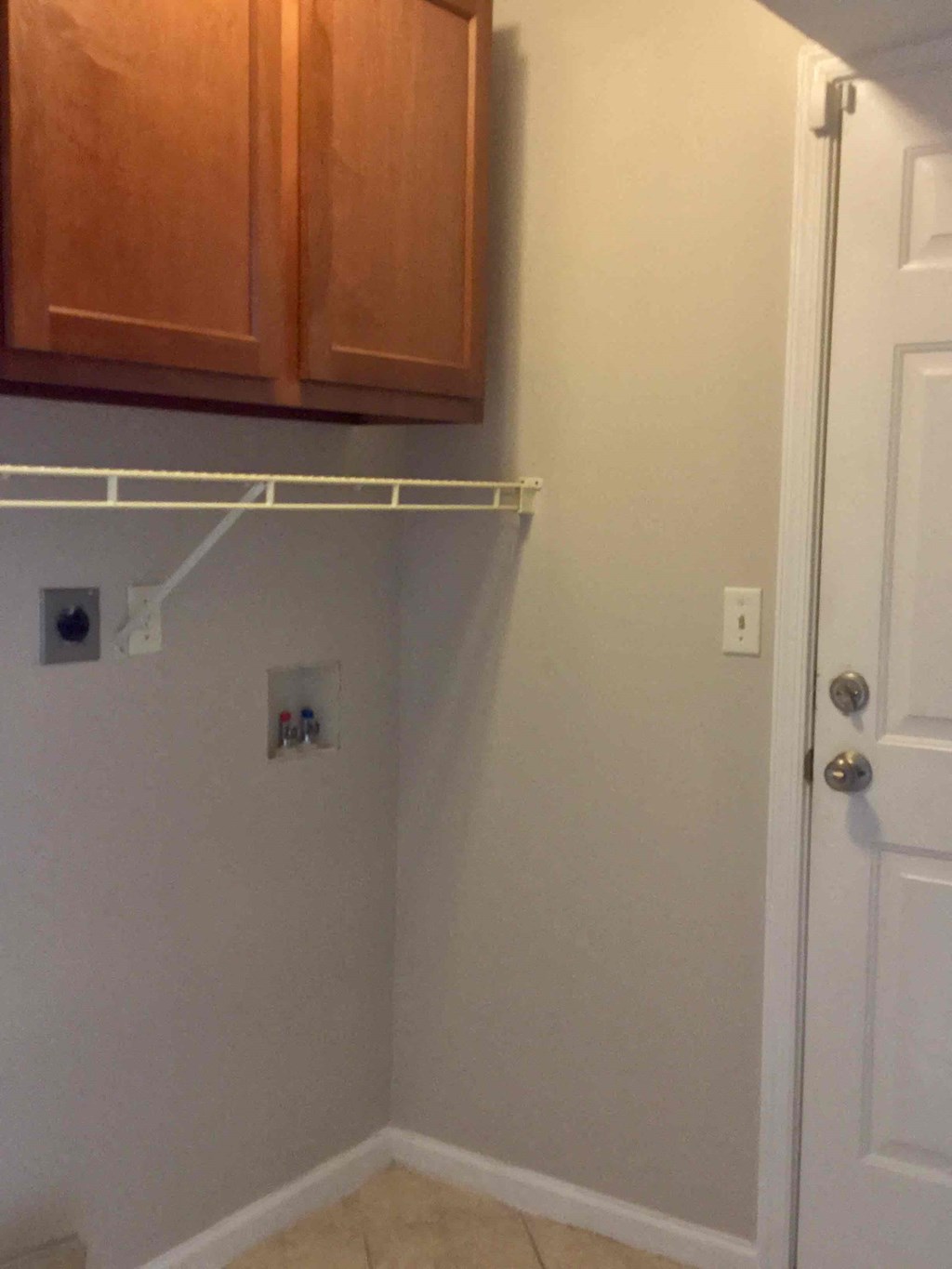 an empty closet with a white wall and wooden cabinets