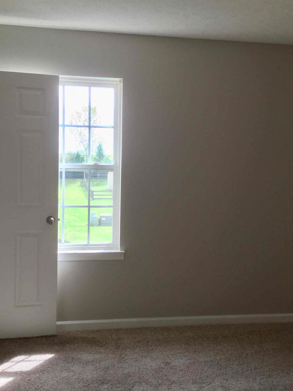 an empty room with a window and a white door