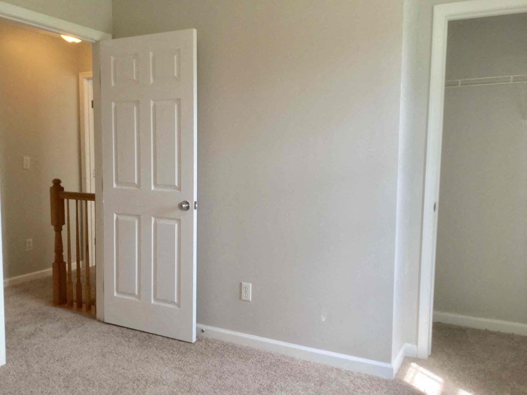 a room with a white door and a hallway with a staircase