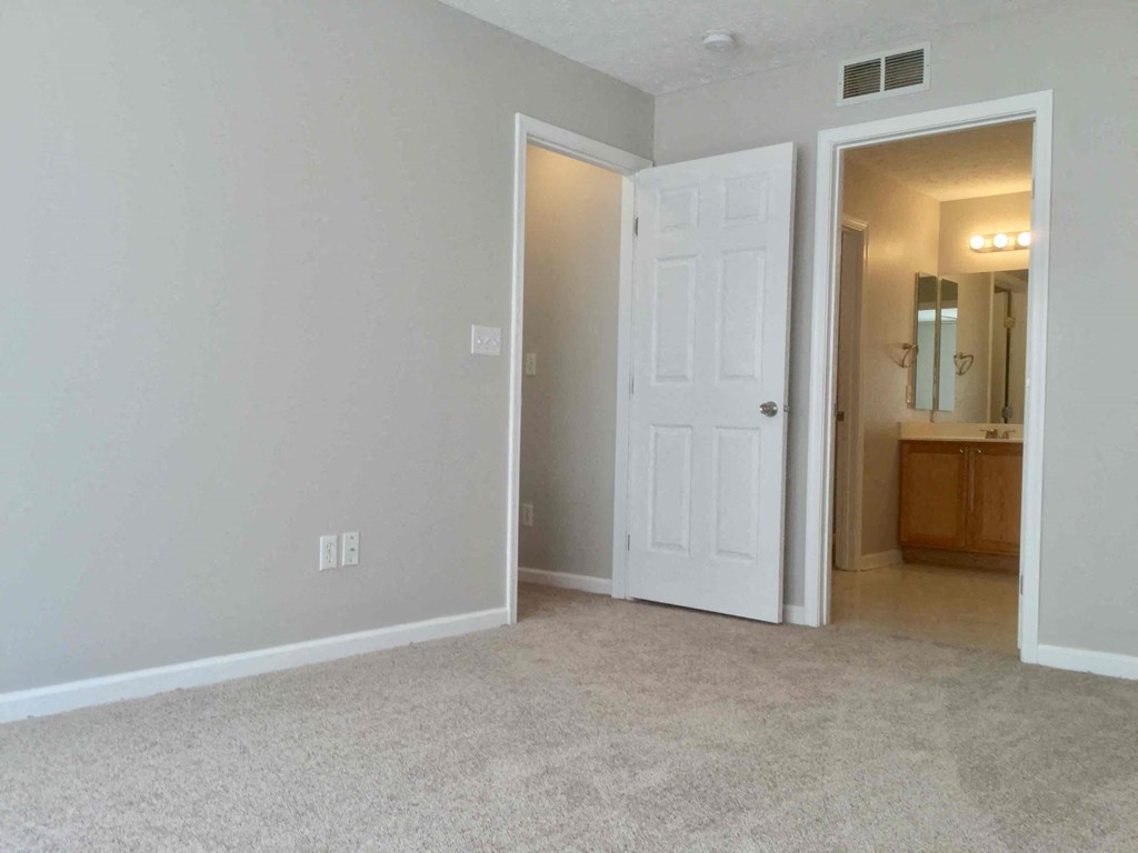 an empty living room with a white door to a bathroom