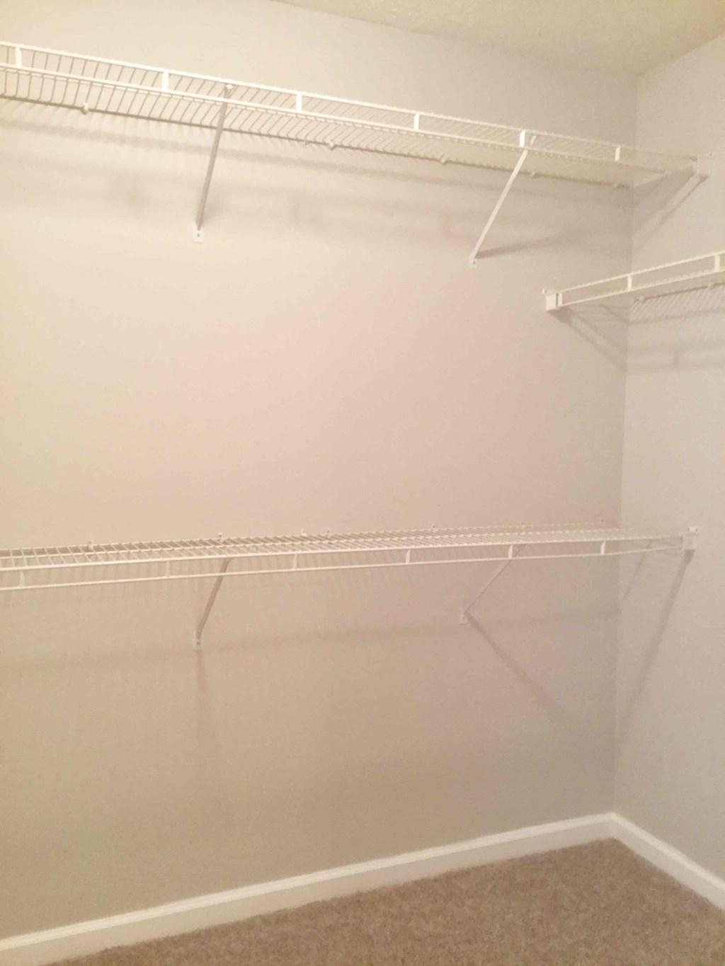 a walk in closet with white walls and empty shelves