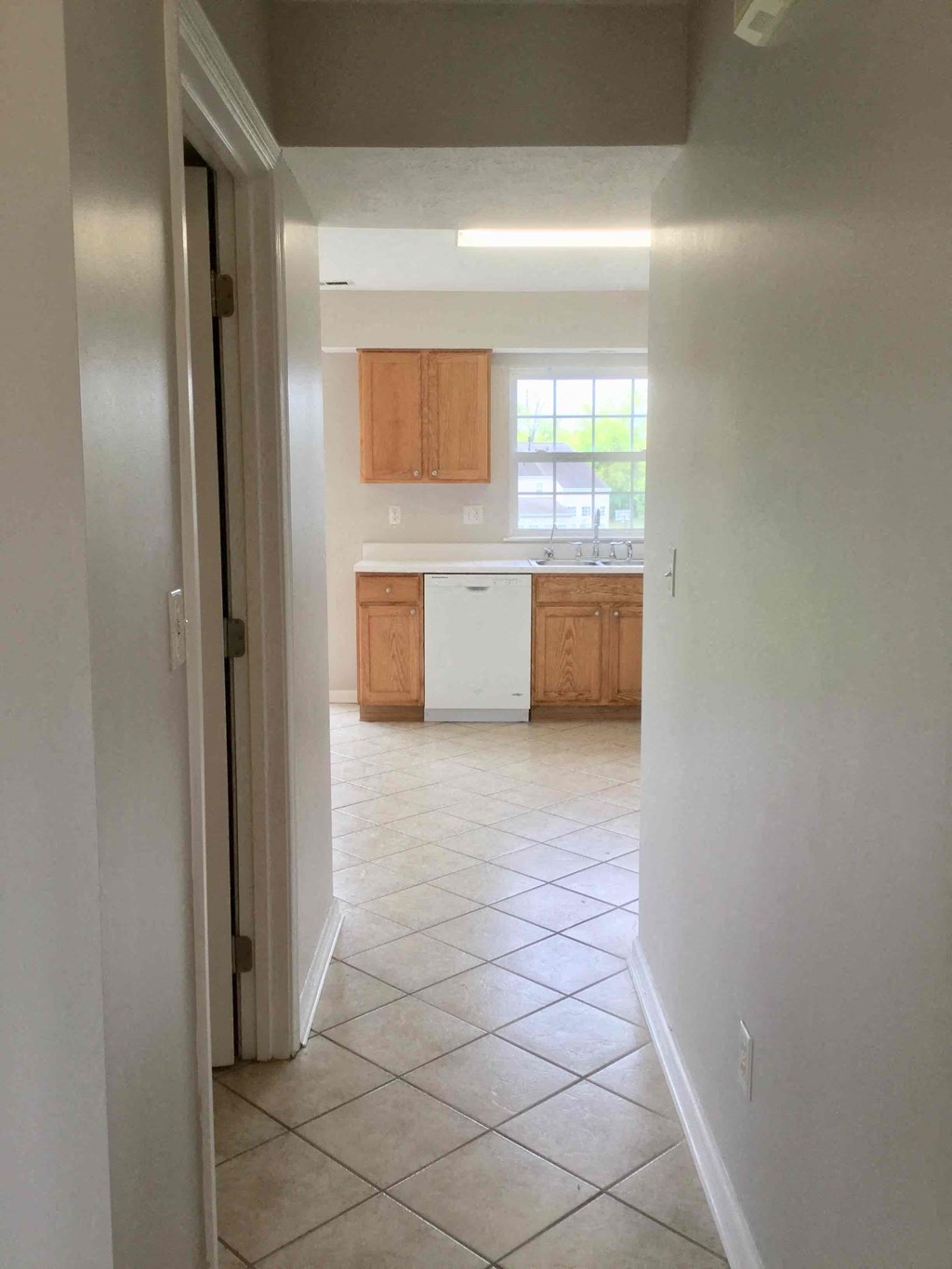 an empty kitchen with a tiled floor and wooden cabinets