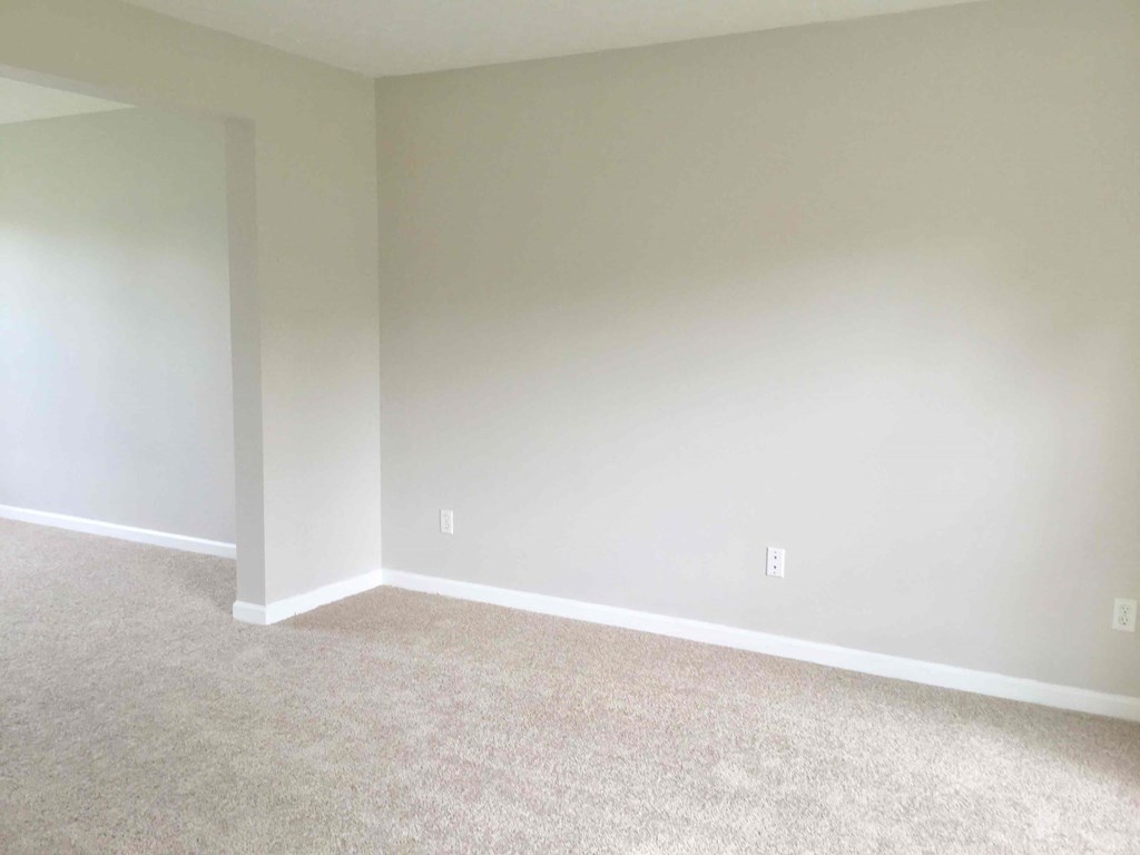 an empty room with white walls and carpet