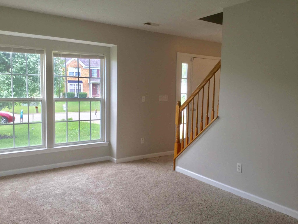 a living room with a staircase and a large window