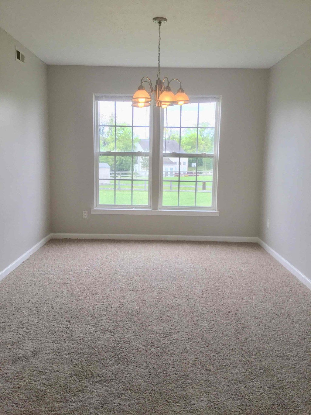 an empty living room with large windows and carpet