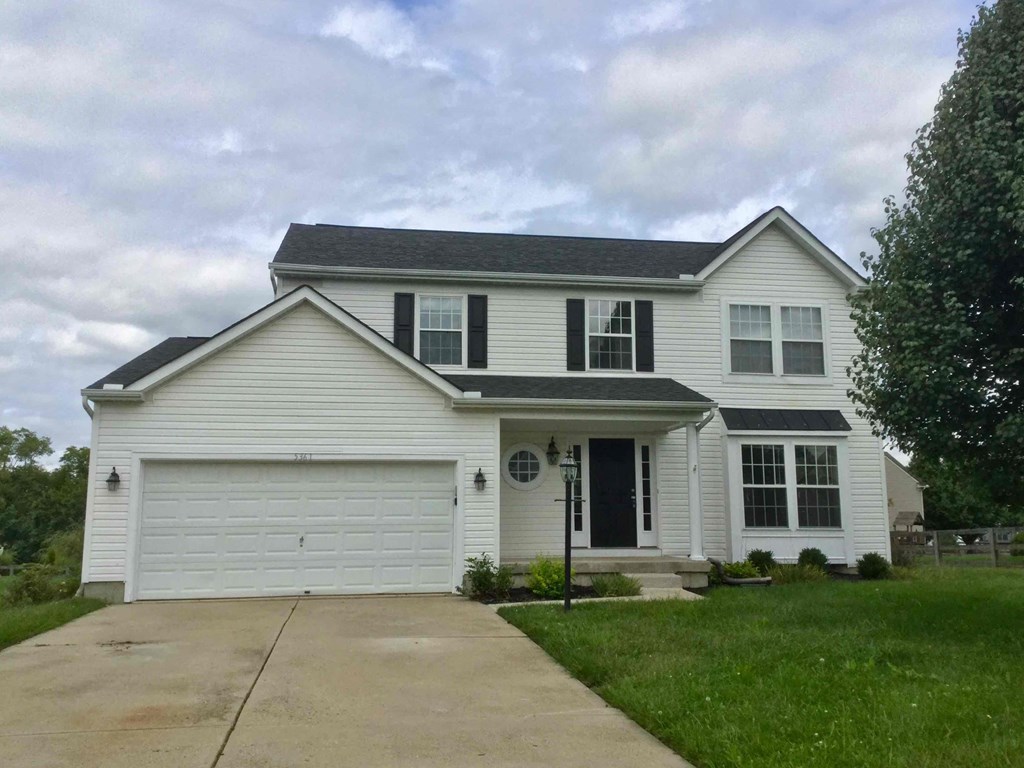 a white house with black shutters and a driveway