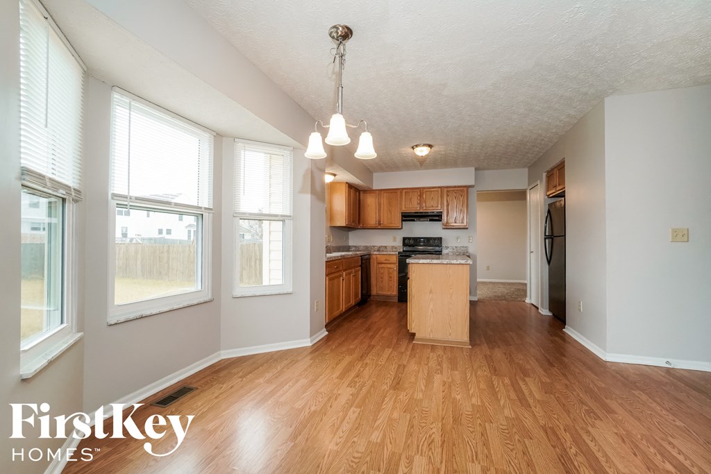 the kitchen and living room of an empty house with wood flooring and white walls