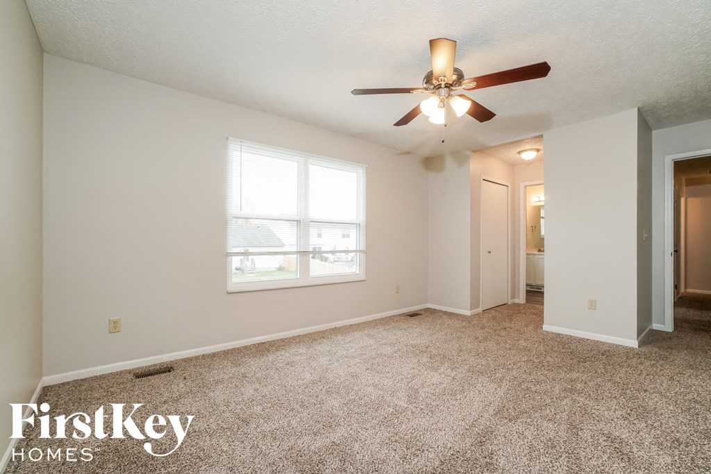 a living room with carpet and a ceiling fan