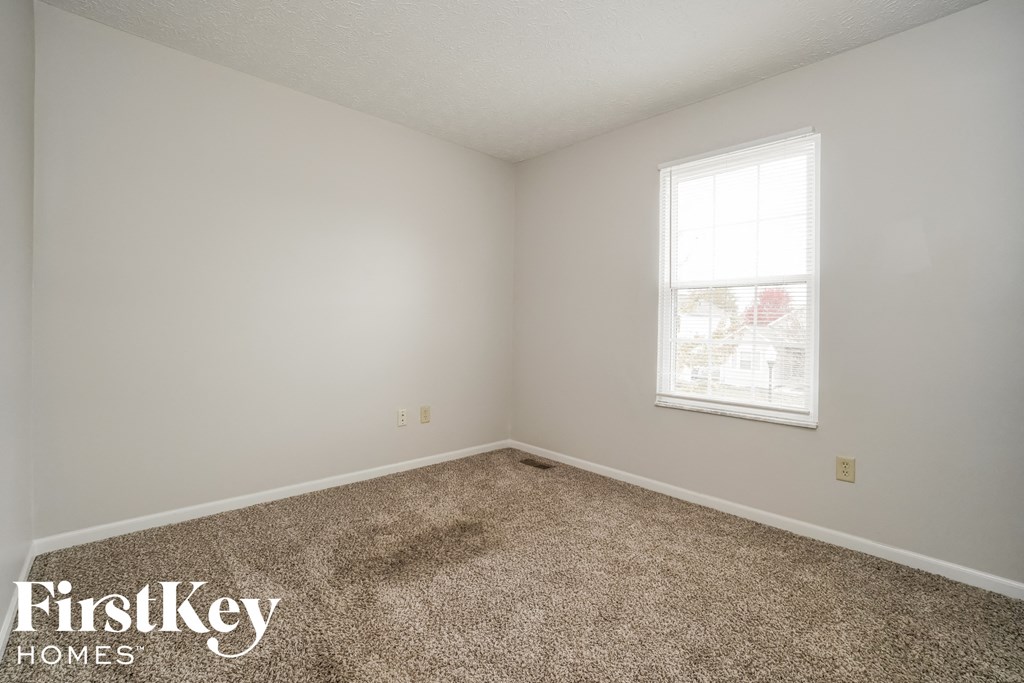 a small room with carpet and a window