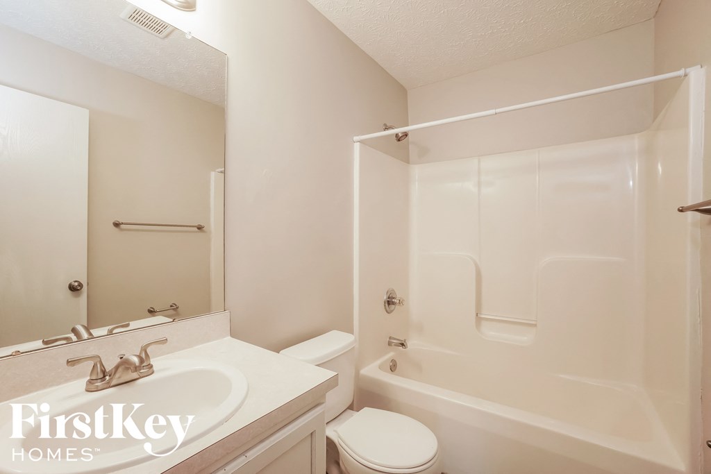 a white bathroom with a shower toilet and sink