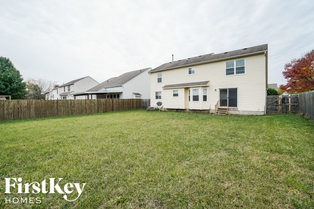 the backyard of a white house with a yard and a fence