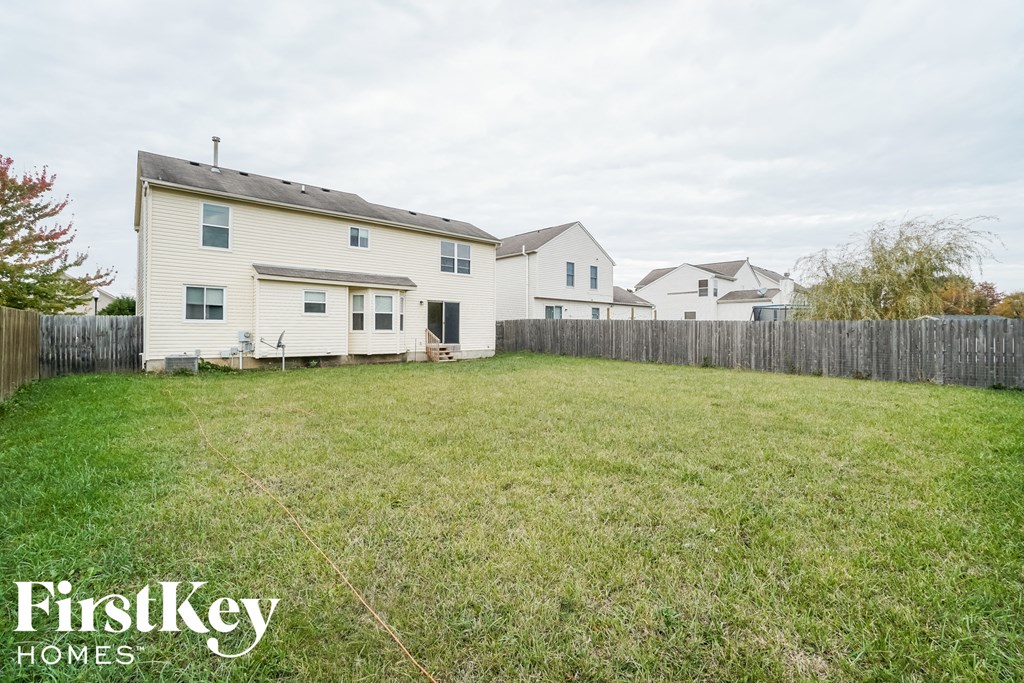 the backyard of a white house with a yard and a fence