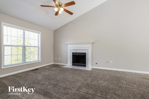 A spacious living room with a fireplace and a ceiling fan.