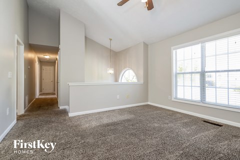 A spacious room with a carpeted floor and a ceiling fan.