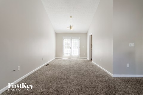 A carpeted hallway with a light on the ceiling and a door at the end.