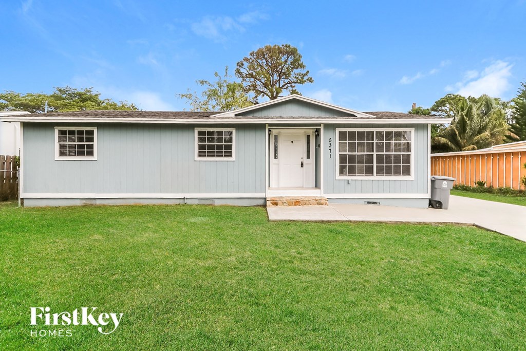 a small blue house with a lawn and a driveway
