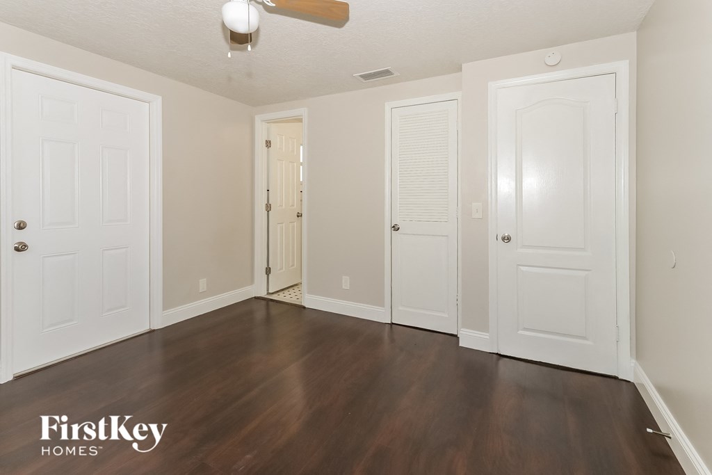 an empty living room with white doors and wood flooring