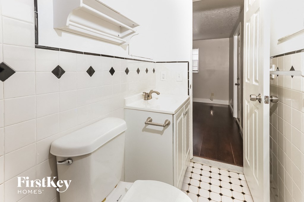a white bathroom with black and white tile and a white toilet