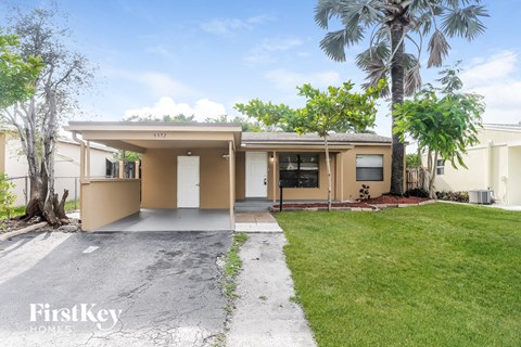 a home with a driveway and a lawn and palm trees