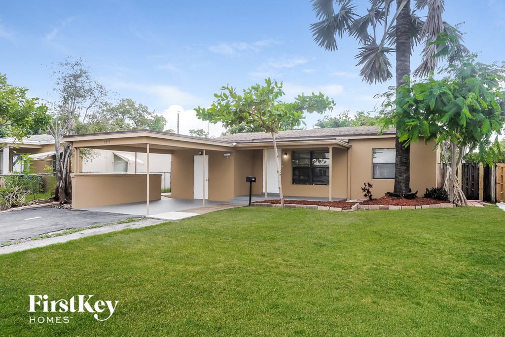a beige house with a lawn and palm trees