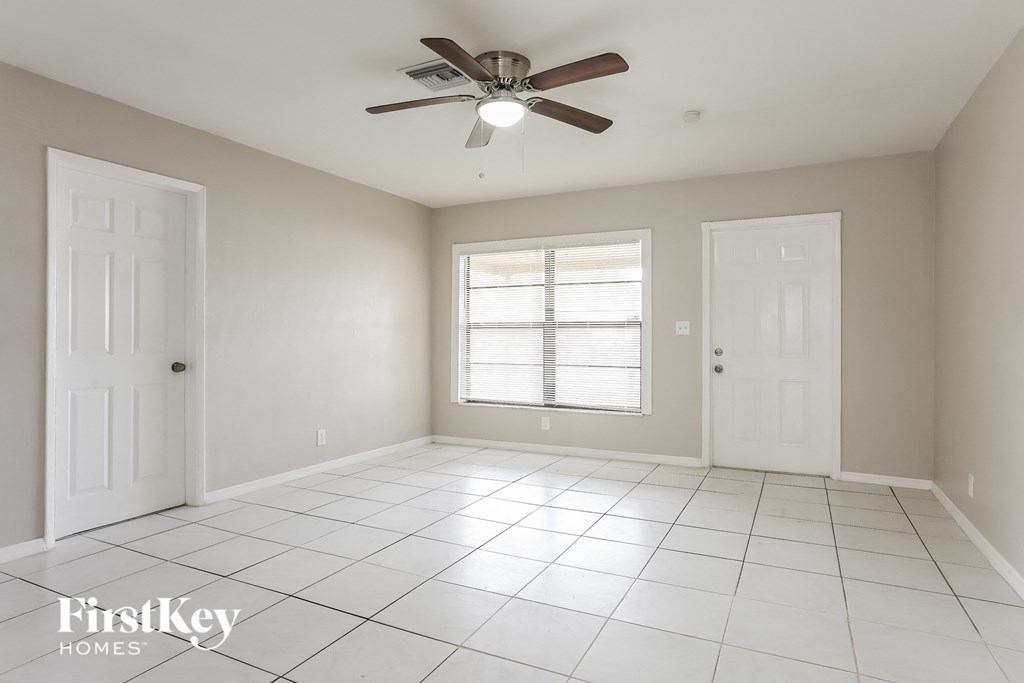 an empty living room with a ceiling fan and a window