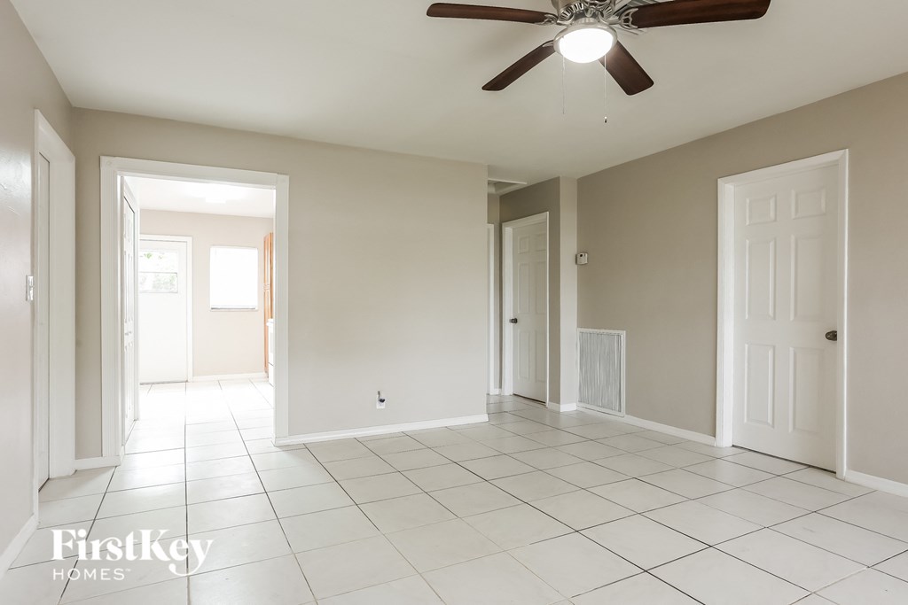 an empty living room with a ceiling fan and a tiled floor