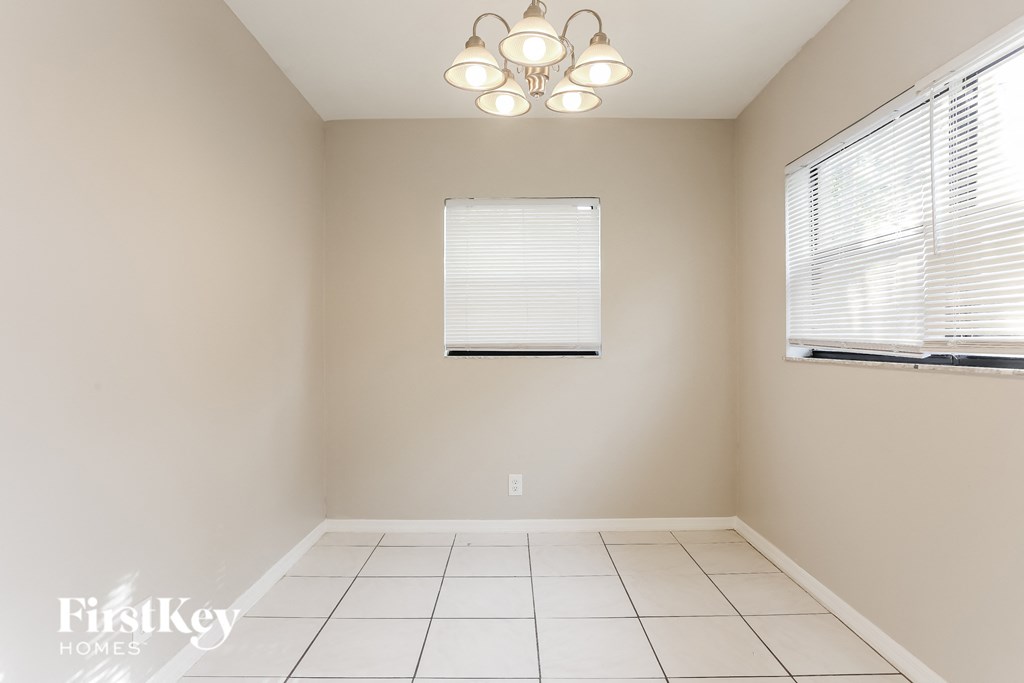 a dining room with a window and a white tiled floor and a light fixture