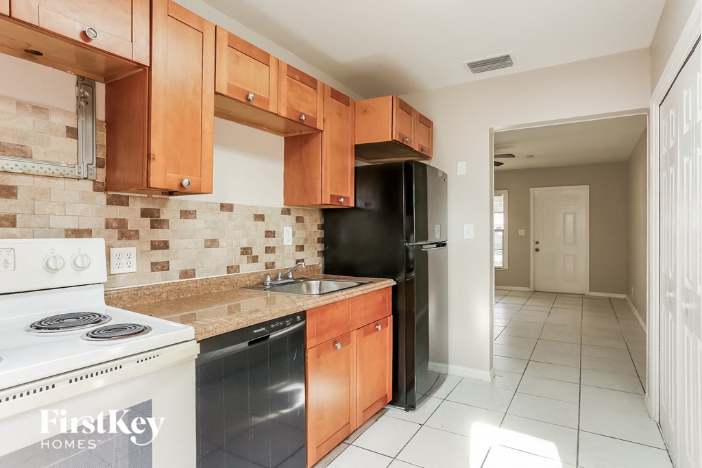 a kitchen with wood cabinets and white appliances and a black refrigerator
