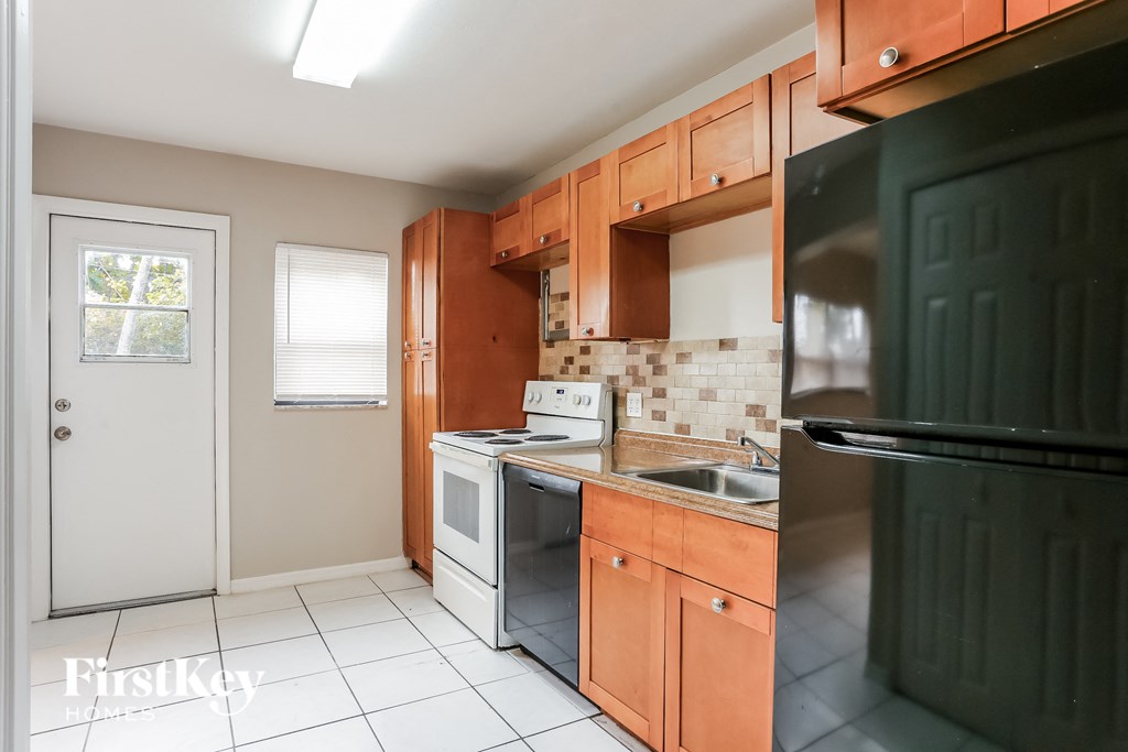 a kitchen with wooden cabinets and a black refrigerator and a sink