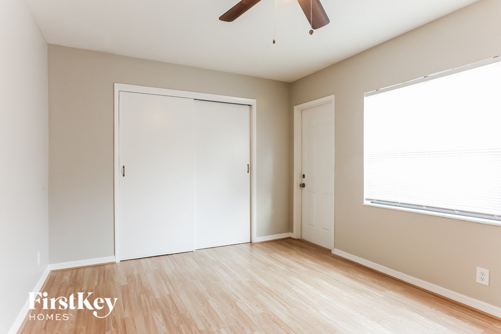 a bedroom with a closet and a window and a ceiling fan