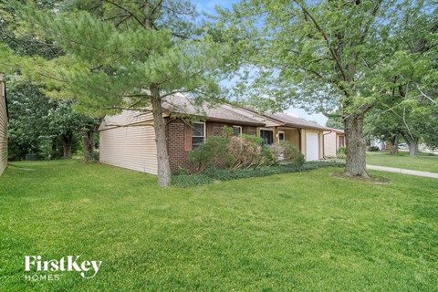 A house with a lawn and trees in front of it.