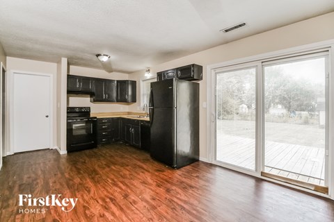 A kitchen with black appliances and wooden floors.